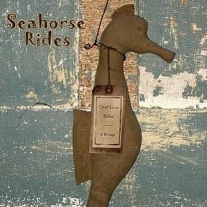Könnte beinhalten: Ein braunes, hölzernes Seepferdchen mit einem Etikett, auf dem "Seahorse Rides 3 inches" steht. Das Seepferdchen hängt an einer Schnur und befindet sich vor einem blauen und braunen Holzhintergrund. Der Text "Sassafras Hill Primitives" ist am unteren Rand des Bildes sichtbar.