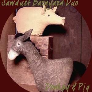 Op de afbeelding: Een handgemaakt setje van een ezel en een varken. De ezel is grijs en het varken is lichtbruin. Ze zitten allebei op een houten kist. De tekst "Sawdust Barnyard Duo" staat bovenaan de afbeelding in bruin. De tekst "Donkey & Pig" staat onderaan de afbeelding in bruin.