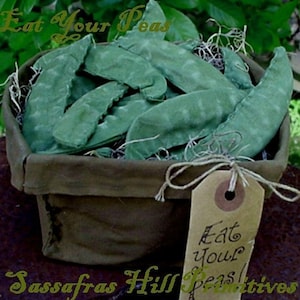 May include: A green fabric basket filled with green fabric pea pods. The basket has a brown fabric tag that says "Eat your peas".