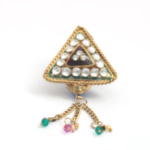 May include: A gold-coloured triangular pendant with clear, round stones and a dark centre. The pendant has a green border and a rope-like trim. Dangling from the bottom are gold chains with green, pink, and yellow beads.