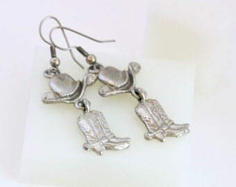 Brincos de caubói, pingentes de metal prateado com chapéu e bota de caubói.
