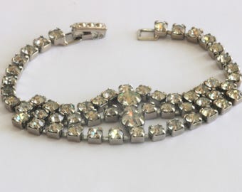 May include: A silver-toned bracelet with two rows of clear, square-cut rhinestones. The bracelet has a decorative center section with larger stones and a clasp closure. The rhinestones sparkle against the light background.