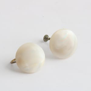 May include: A pair of white pearl-like earrings with silver screw-back closures.