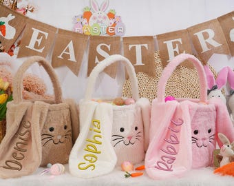 Peut inclure: Trois paniers en forme de lapin de Pâques avec des oreilles en fourrure. Les paniers sont de couleur marron, blanc et rose et portent les noms "Denise", "Sophia" et "Lapin" brodés dessus. Les paniers sont décorés d'une bannière en toile de jute qui dit "Pâques".