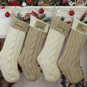 May include: Four cream and brown knitted stockings with gold name tags. The tags read "Frank", "Dad", "Emily", and "Mom".
