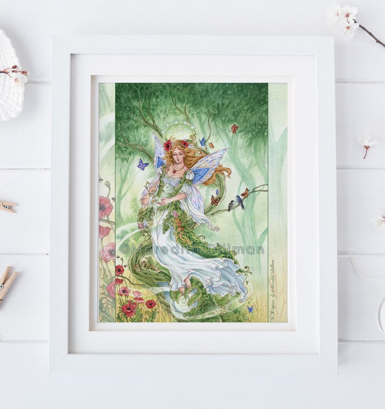 May include: A watercolor painting of a fairy with blue wings and a white dress, surrounded by green leaves, flowers, and butterflies. The fairy is holding a wreath of flowers in her hands. The painting is titled "The Spirit of Spring" by Meredith Dillman.