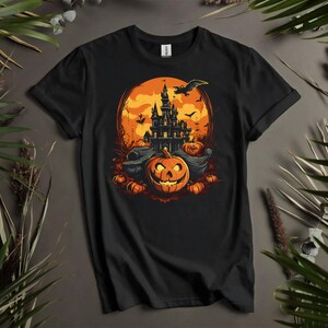 Puede incluir: Camiseta negra con un dise&ntilde;o de Halloween. El gr&aacute;fico incluye una calabaza tallada, un castillo embrujado, murci&eacute;lagos y una luna llena. El dise&ntilde;o es en tonos naranja, negro y amarillo. La camiseta se muestra sobre un fondo neutro con vegetaci&oacute;n.