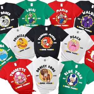 May include: A selection of vibrant t-shirts showcasing Super Mario characters. Each tee features a character's name, a graphic, and the text "EST 1985 SUPER MARIO" in a circular design. The shirts come in black, green, red, and white.