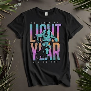 May include: Black t-shirt with a graphic print of a cartoon space ranger running. The text "To Infinity and Beyond" is printed below the graphic. The graphic is in shades of blue, pink, and green.
