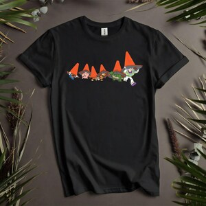 Puede incluir: Camiseta negra con un dise&ntilde;o de dibujos animados de gnomos con conos de tr&aacute;fico naranjas como sombreros, con Buzz Lightyear. El dise&ntilde;o est&aacute; en el pecho. La camiseta es de un material suave.