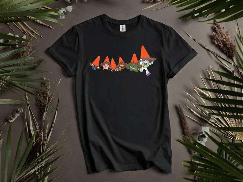 Puede incluir: Camiseta negra con un dise&ntilde;o de dibujos animados de gnomos con conos de tr&aacute;fico naranjas como sombreros, con Buzz Lightyear. El dise&ntilde;o est&aacute; en el pecho. La camiseta es de un material suave.