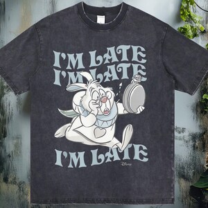 May include: Dark gray t-shirt featuring the White Rabbit from Alice in Wonderland, running with a pocket watch. The text "I'M LATE" is repeated three times in a light blue font. The shirt has a vintage, distressed look.