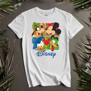 Könnte beinhalten: Weißes T-Shirt mit einem bunten Motiv von Mickey Mouse, Donald Duck, Goofy und Pluto. Das Motiv ist von einem bunten, abstrakten Design umgeben. Der Text "DISNEY" ist unter dem Motiv aufgedruckt.