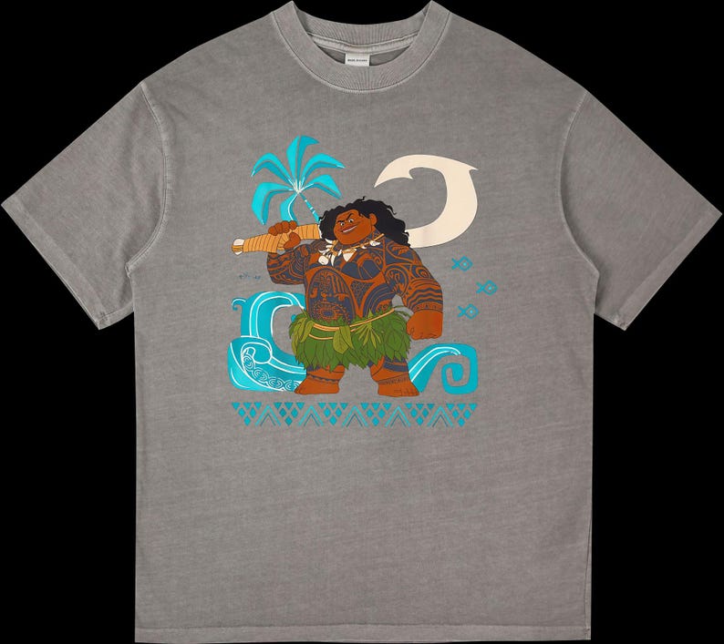Puede incluir: Camiseta gris con una ilustraci&oacute;n de dibujos animados de un personaje polinesio. El dise&ntilde;o incluye una palmera, olas y peces en tonos azules y blancos. El personaje tiene tatuajes, una falda de hierba y un arma.