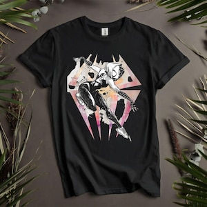 May include: Black t-shirt featuring a graphic of a superhero in a dynamic pose. The design is in black and white with watercolor-style accents of pink, orange, and yellow. The superhero is set against a geometric background.