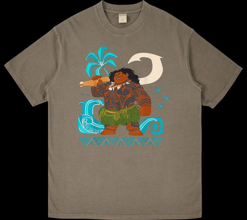 Puede incluir: Camiseta verde oliva descolorida con una ilustraci&oacute;n de dibujos animados de una figura polinesia. La figura tiene tatuajes, una falda de hierba y un arma. El dise&ntilde;o incluye una palmera, olas y una luna creciente.