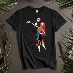 May include: Black t-shirt with a graphic of Jack Skellington and Sally from The Nightmare Before Christmas. Jack is in a black suit with red accents, and Sally is in a patchwork dress with red hair. The design is centered on the shirt.