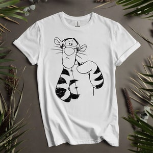 Könnte beinhalten: Weißes T-Shirt mit einer Schwarz-Weiß-Illustration von Tigger aus Winnie Puuh. Die Zeichentrickfigur ist mit seinen charakteristischen Streifen und einem nachdenklichen Ausdruck dargestellt. Das Shirt besteht aus einem weichen, bequemen Material.