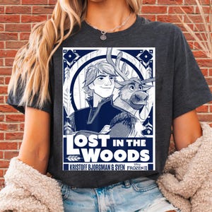 Puede incluir: Camiseta gris oscuro con un gr&aacute;fico de Frozen II de Disney. El dise&ntilde;o incluye a Kristoff, Sven y el texto "LOST IN THE WOODS". El gr&aacute;fico est&aacute; en tonos de azul y blanco.