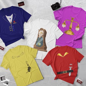 Puede incluir: Cinco camisetas diferentes con personajes de La Bella y la Bestia de Disney. Las camisetas son de varios colores, incluyendo azul, blanco, amarillo, rojo y morado. Cada camiseta presenta un personaje u objeto diferente de la película, como un reloj, un candelabro, una rosa, una espada y un traje.