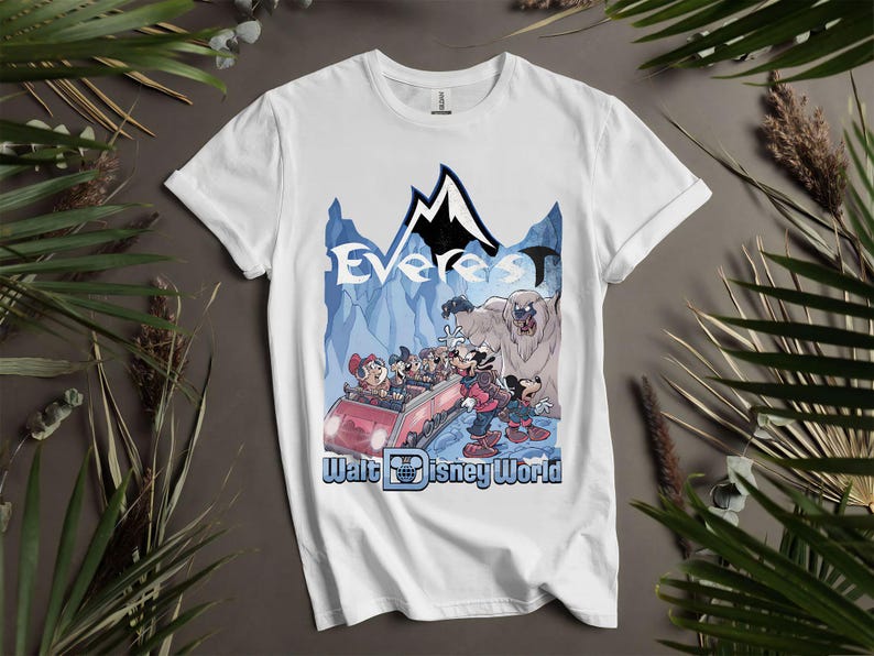 Puede incluir: Camiseta blanca con un gr&aacute;fico colorido de una monta&ntilde;a rusa con Mickey Mouse y sus amigos. El dise&ntilde;o incluye la palabra "Everest" y "Walt Disney World" en una escena de monta&ntilde;a azul y negra.