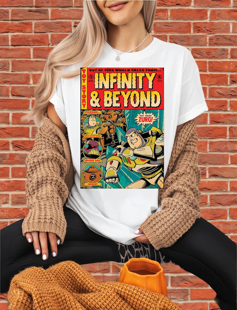 Puede incluir: Camiseta blanca con un dise&ntilde;o de c&oacute;mic que presenta las palabras "INFINITY & BEYOND" y personajes de Toy Story. El gr&aacute;fico incluye el texto "ZURG!" y "TOY STORY".