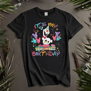 Pu&ograve; includere: Maglietta nera con un personaggio di pupazzo di neve bianco che tiene una torta e dei regali. Il testo "It's my birthday" &egrave; stampato sulla maglietta.