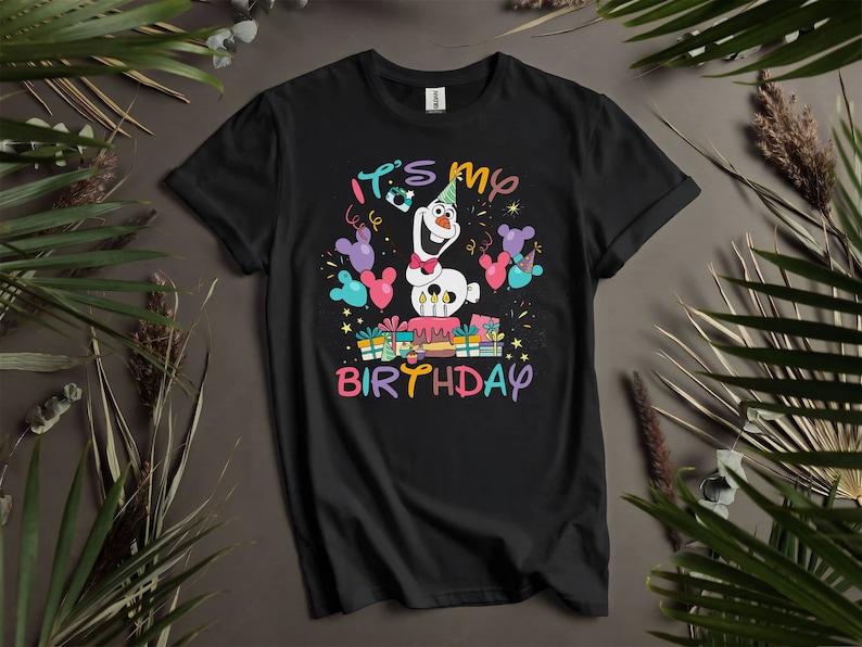 Pu&ograve; includere: Maglietta nera con un personaggio di pupazzo di neve bianco che tiene una torta e dei regali. Il testo "It's my birthday" &egrave; stampato sulla maglietta.