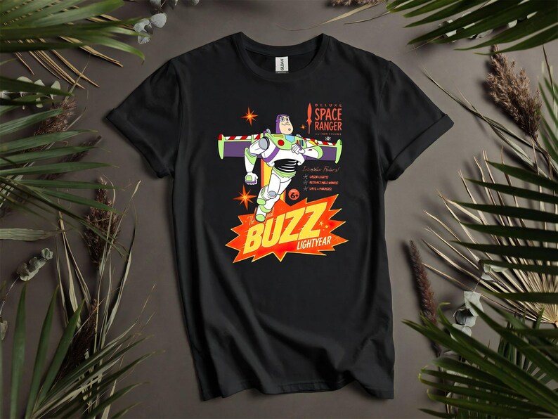 Puede incluir: Camiseta negra con un gr&aacute;fico de Buzz Lightyear de la pel&iacute;cula Toy Story. El dise&ntilde;o incluye a Buzz con su traje de guardi&aacute;n espacial, las palabras "BUZZ LIGHTYEAR" y otro texto. La camiseta est&aacute; rodeada de hojas verdes.