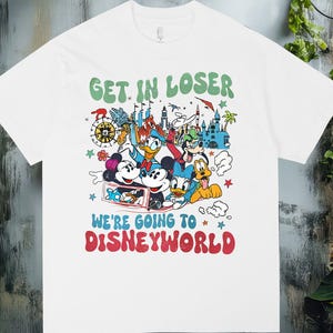 Puede incluir: Camiseta blanca con un gráfico colorido con Mickey Mouse, Minnie Mouse, Donald Duck, Goofy y otros personajes de Disney. La camiseta tiene el texto "GET IN LOSER" en verde y "WE'RE GOING TO DISNEYWORLD" en rojo.