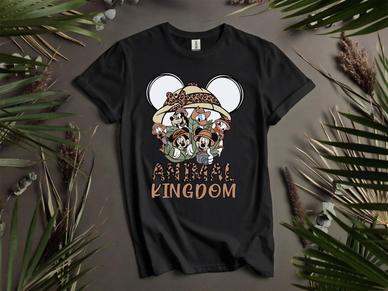 Puede incluir: Camiseta negra con un gr&aacute;fico de Mickey Mouse y sus amigos vestidos como exploradores de safari. El gr&aacute;fico incluye un sombrero de estampado de leopardo y el texto "Animal Kingdom".