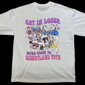 Puede incluir: Camiseta blanca con un gráfico colorido con personajes de Disney y el texto "GET IN LOSER WE'RE GOING TO DISNEYLAND 70TH". El diseño incluye Mickey y Minnie Mouse, el Pato Donald y Goofy.