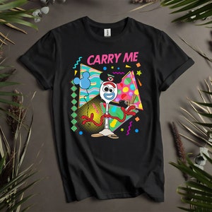May include: Black t-shirt featuring a colourful graphic of a toy character with the text "Carry Me".