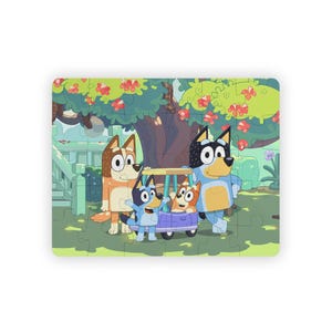 May include: A rectangular jigsaw puzzle featuring a colorful cartoon illustration of four blue and red heeler dogs. The scene depicts the characters standing near a small purple golf cart under a large tree with green leaves and red flowers.