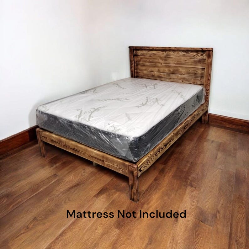 Puede incluir: Un marco de cama de madera r&uacute;stico con una cabecera de listones. El marco de la cama est&aacute; hecho de madera recuperada y tiene un acabado natural. El colch&oacute;n no est&aacute; incluido. "Mattress Not Included" est&aacute; escrito en negro en el suelo.