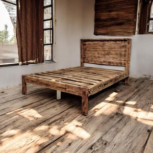 Puede incluir: Un marco de cama de madera r&uacute;stico con una cabecera y un piecero de listones. El marco de cama est&aacute; hecho de madera recuperada y tiene un acabado natural y desgastado.