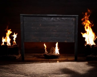 Puede incluir: Una cabecera de cama de madera negra con un acabado rústico. La cabecera está colocada sobre un fondo oscuro con llamas a cada lado.