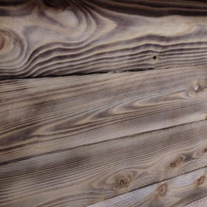 Puede incluir: Primer plano de una superficie de madera desgastada con un patr&oacute;n de veta de madera natural. La madera es de color marr&oacute;n claro con vetas y nudos marrones m&aacute;s oscuros. La superficie est&aacute; formada por varias tablas de madera que est&aacute;n unidas.