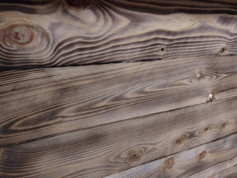 Puede incluir: Primer plano de una superficie de madera desgastada con un patr&oacute;n de veta de madera natural. La madera es de color marr&oacute;n claro con vetas y nudos marrones m&aacute;s oscuros. La superficie est&aacute; formada por varias tablas de madera que est&aacute;n unidas.