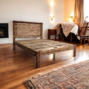Puede incluir: Un marco de cama de madera r&uacute;stico con una cabecera y un piecero de listones. El marco de cama est&aacute; hecho de madera recuperada y tiene un acabado natural y desgastado.
