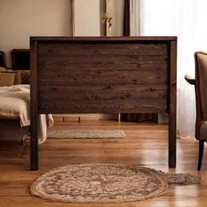 May include: A dark brown wooden headboard with horizontal slats. The headboard is standing on a wooden floor with a rug in front of it.