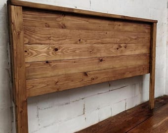 Puede incluir: Una cabecera de cama de madera rústica con un tinte marrón natural. La cabecera está hecha de tablones de madera horizontales y tiene un diseño simple y rectangular.