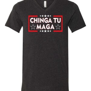 May include: A dark gray V-neck t-shirt with the text "CHINGA TU MAGA" in a red box with white stars.