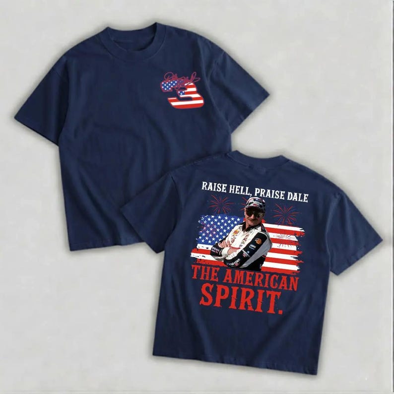 a navy blue t-shirt with a graphic design on the back, depicting a person in a racing suit and sunglasses. The design includes an American flag and the text "Raise Hell, Praise Dale" and "The American Spirit."