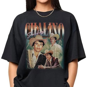 May include: Black t-shirt featuring a vintage-style graphic of Chalino Sanchez. The design includes multiple images of the singer in a cowboy hat, with the name "Chalino Sanchez" in a retro font. The background has a lightning bolt effect.