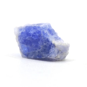 May include: A raw, unpolished mineral specimen featuring a vibrant blue crystalline structure with translucent sections and opaque white edges. The stone has an irregular, jagged shape with a rough, textured surface showing natural facets.
