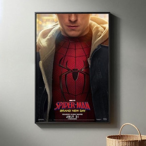 May include: Framed movie poster featuring the Spider-Man character. The poster has a red and black color scheme, with the Spider-Man logo and the text "SPIDER-MAN BRAND NEW DAY" and "JULY 31". The image shows a person wearing the Spider-Man suit.