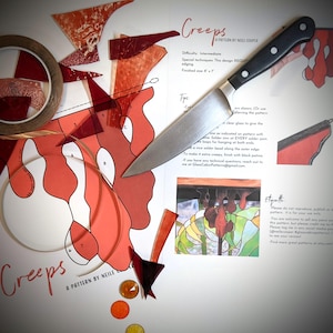 May include: A craft project layout with a knife, glass pieces, and a pattern titled "Creeps." The pattern includes instructions and diagrams for a stained glass project. Various colored glass pieces and tape are also present.