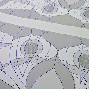 Puede incluir: Una plantilla de papel para vidrieras con secciones numeradas delineadas en tinta azul. El dise&ntilde;o consta de formas org&aacute;nicas grises y blancas con centros circulares. El texto en la p&aacute;gina incluye "Home" y "A pattern by Neill Cooper".
