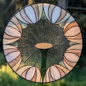 以下が含まれることがあります： 幾何学模様のステンドグラスの丸窓。中央は緑色で、ピンクと白の花びらで囲まれています。